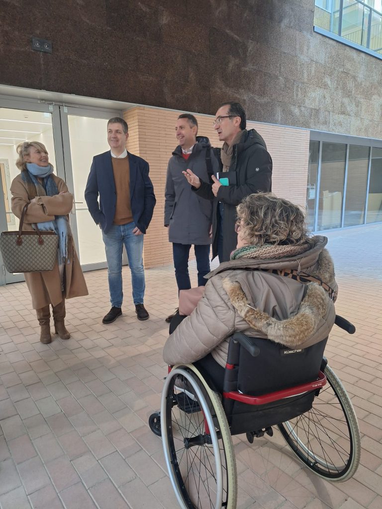 Representantes del CERMI y de la OUAD en el patio de la Facultad de Filosofía y letras de pie escuchando la explicación